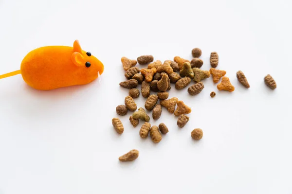 Vue de dessus de nourriture sèche pour chat près de souris en caoutchouc orange isolée sur blanc — Photo de stock