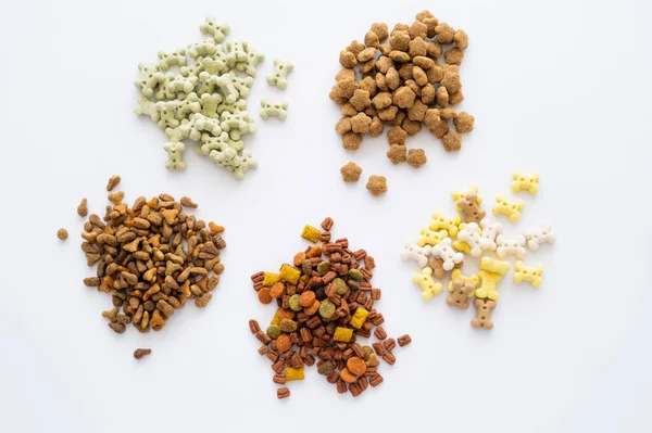Vista superior de diferentes alimentos secos e guloseimas saborosas para animais de estimação isolados em branco — Fotografia de Stock