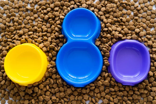 Top view of colorful plastic bowls on dry pet food — Stock Photo