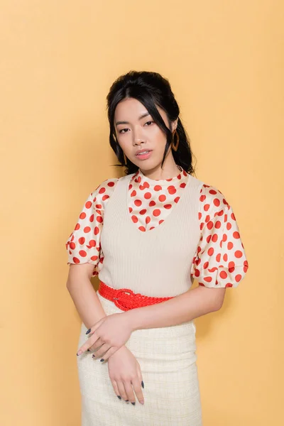 Porträt des stilvollen asiatischen Modells, das auf orangefarbenem Hintergrund in die Kamera blickt — Stockfoto