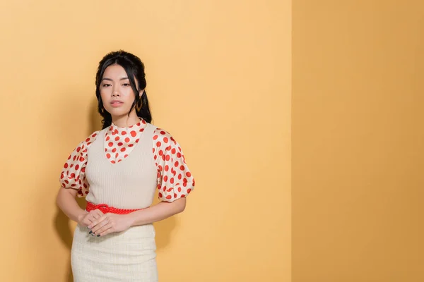 Bonita mujer asiática en ropa vintage sobre fondo naranja - foto de stock