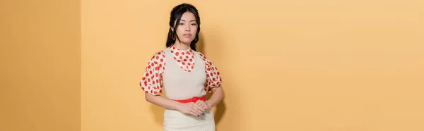 Fashionable asian woman in dress and blouse on orange background, banner — Stock Photo