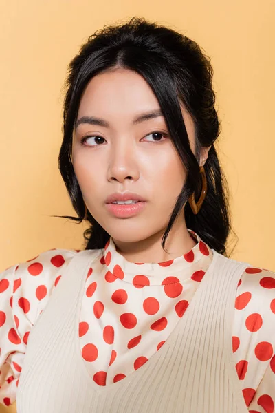 Portrait of stylish asian woman looking away isolated on orange — Stock Photo