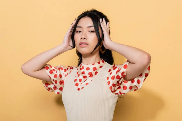 Fashionable asian model looking at camera on orange background — Stock Photo