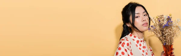Donna asiatica in abiti retrò che tiene fiori su sfondo arancione, banner — Foto stock