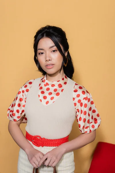 Junge asiatische Modell in Vintage-Kleidung hält Handtasche auf orangefarbenem Hintergrund — Stockfoto