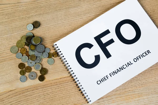 Top view of coins near notebook with cfo lettering on desk — Stock Photo