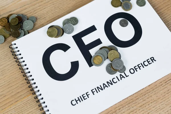 Close up view of coins near notebook with cfo lettering on desk — Stock Photo