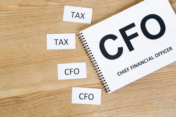 Vista dall'alto di notebook con cfo e lettering chief financial officer vicino a carte con abbreviazione sulla scrivania — Foto stock