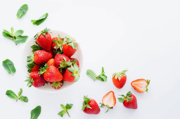 Top view of fresh strawberries and blurred mint leaves on white background — Stock Photo
