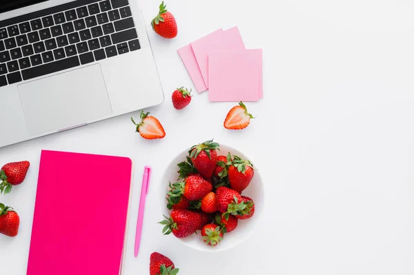 Vista dall'alto di fragole fresche vicino notebook e laptop su sfondo bianco — Foto stock