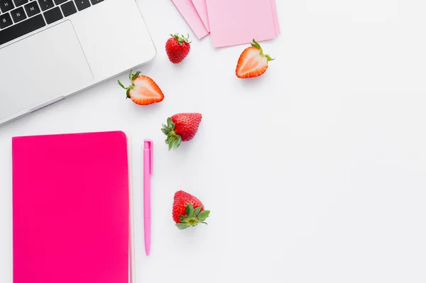 Top view of notebook ear fresh strawberries and laptop on white background — Stock Photo