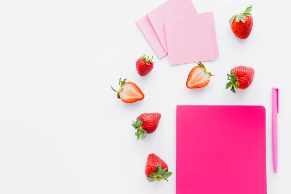 Vue du dessus des fraises mûres près du carnet et des notes collantes sur fond blanc — Photo de stock