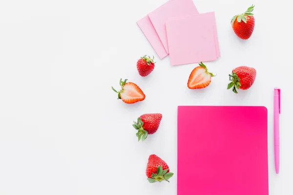 Vista superior de fresas maduras cerca del cuaderno y notas adhesivas sobre fondo blanco - foto de stock