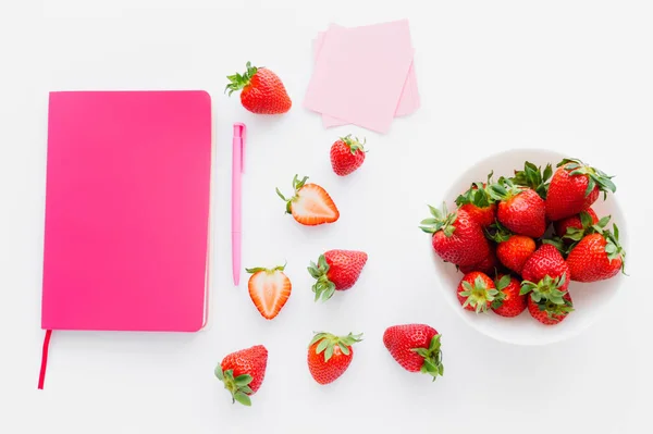 Vista superior del cuaderno rosa y fresas frescas sobre fondo blanco - foto de stock