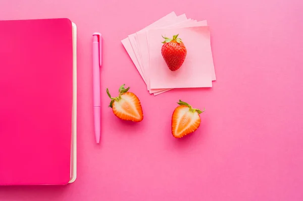 Vista dall'alto di fragole biologiche vicino note appiccicose e notebook su sfondo rosa — Foto stock
