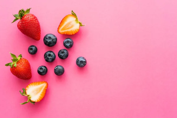 Top view of natural blueberries and strawberries on pink background — Stock Photo