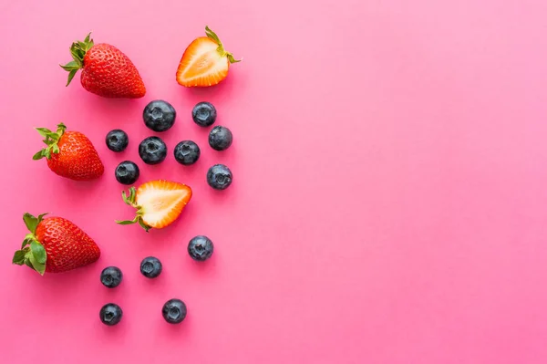 Vista dall'alto di mirtilli freschi e fragole dolci su sfondo rosa — Foto stock