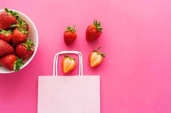 Top view of ripe strawberries and shopping bag on pink background — Stock Photo