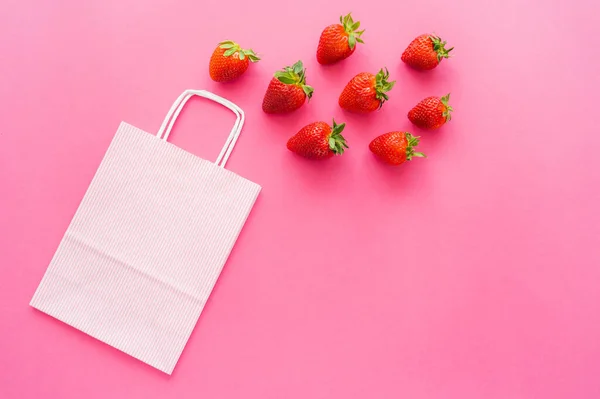 Ansicht der Einkaufstasche in der Nähe von Bio-Erdbeeren auf rosa Hintergrund — Stockfoto