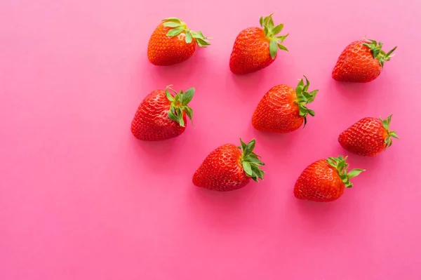 Vista superior de fresas jugosas sobre fondo rosa - foto de stock