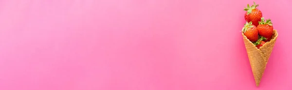 Top view of waffle cone with ripe strawberries on pink surface, banner — Stock Photo