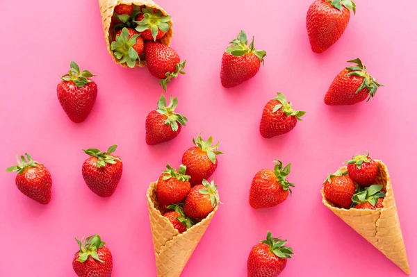 Top view of strawberries near waffle cones on pink background — Stock Photo