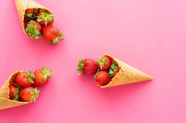 Flat lay of fresh strawberries in waffle cones on pink background — Stock Photo