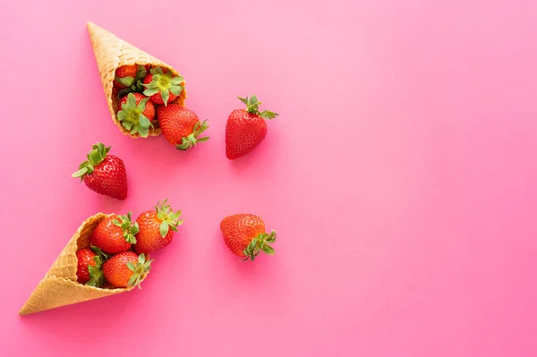 Top view of juicy strawberries in sweet waffle cones on pink background — Stock Photo