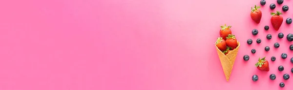 Colocação plana com mirtilos perto de morangos suculentos em cone de waffle no fundo rosa, banner — Fotografia de Stock