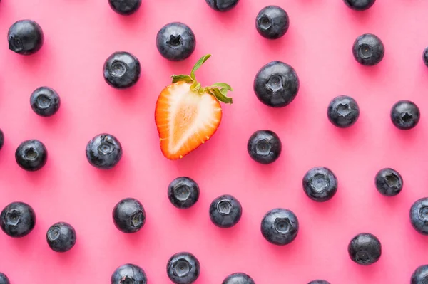 Flat lay of cut strawberry near blueberries on pink background — Stock Photo