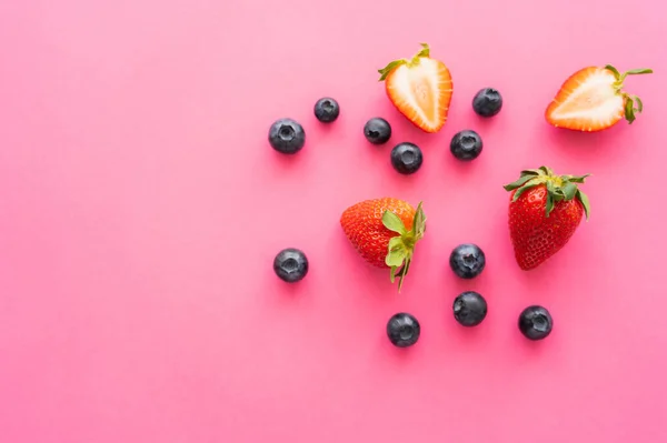 Top view of cut and whole berries on pink background — Stock Photo