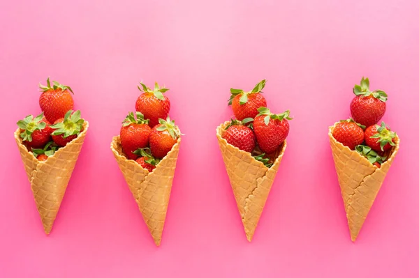 Flat lay with ripe berries with leaves in waffle cones on pink background — Stock Photo