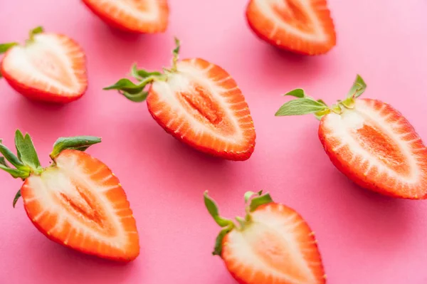 Vista de cerca de fresas cortadas sobre fondo rosa - foto de stock