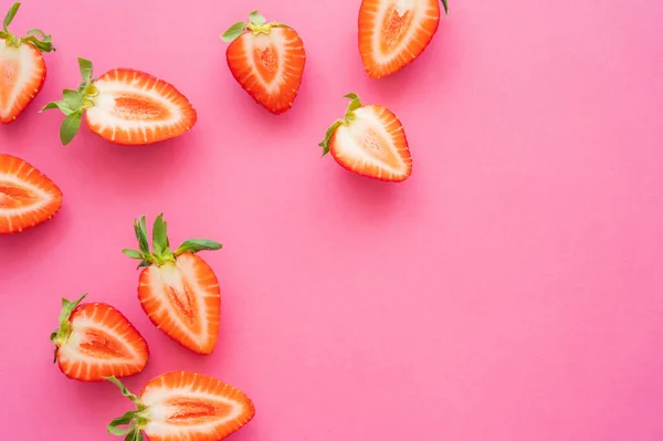 Coucher à plat avec des moitiés de fraises sur fond rose — Photo de stock