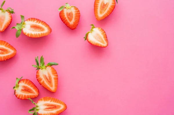 Colocação plana com metades de morangos no fundo rosa — Fotografia de Stock