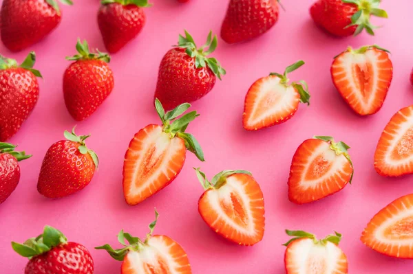 Flat lay with juicy cut and whole strawberries on pink background — Stock Photo