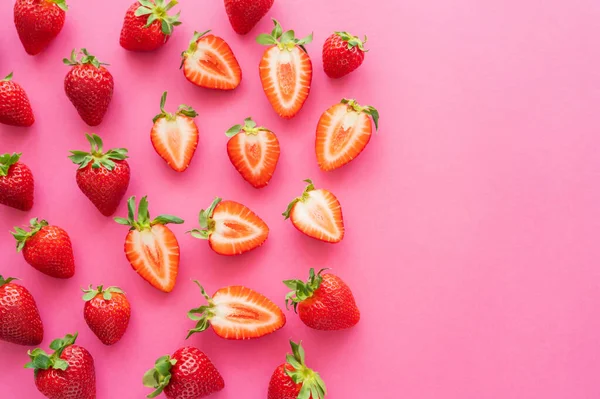 Flat lay with red cut and whole strawberries on pink background — Stock Photo