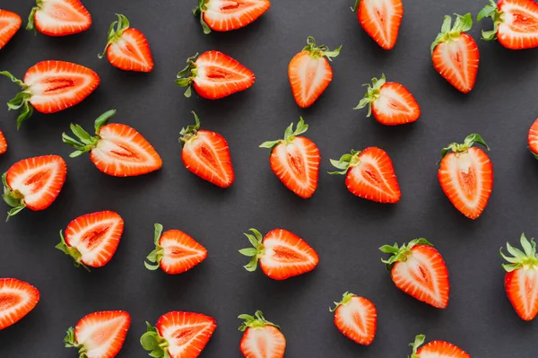 Flache Lage mit geschnittenen Erdbeeren mit Blättern auf schwarzem Hintergrund — Stockfoto