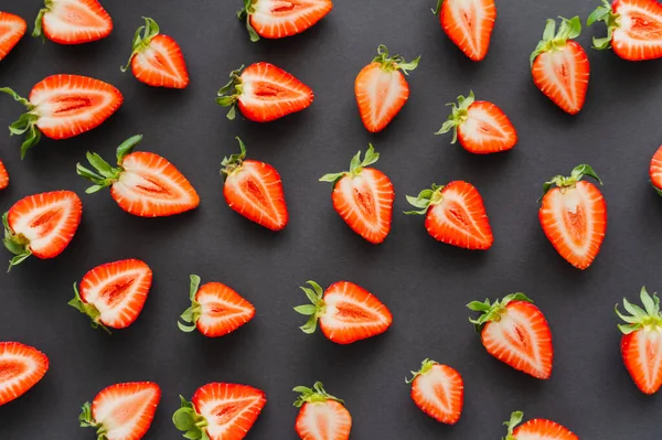 Flat lay with cut strawberries with leaves on black background — Stock Photo