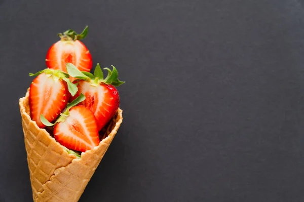 Top view of juicy strawberries in waffle cone on black surface — Stock Photo