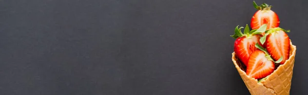 Вид зверху на органічну полуницю у вафельному конусі на чорному тлі, банер — стокове фото