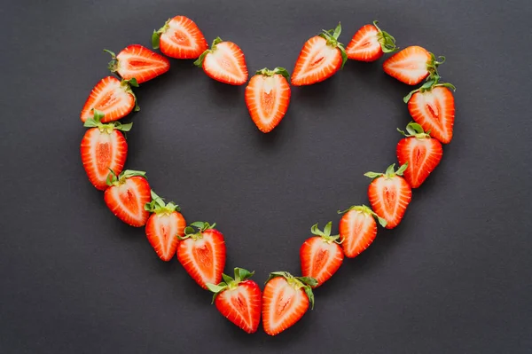 Flat lay with strawberries in heart shape on black background — Stock Photo