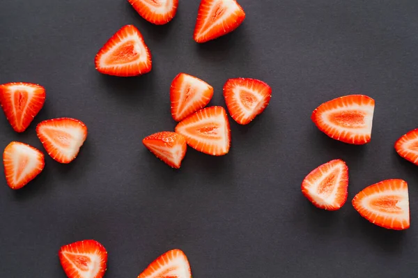 Draufsicht auf geschnittene Erdbeeren auf schwarzem Hintergrund — Stockfoto