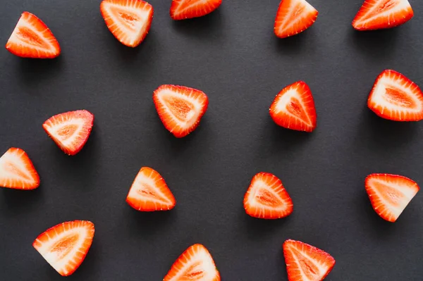 Draufsicht auf geschnittene rote Erdbeeren auf schwarzem Hintergrund — Stockfoto