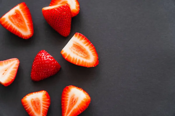 Top view of natural cut strawberries on black background — Stock Photo