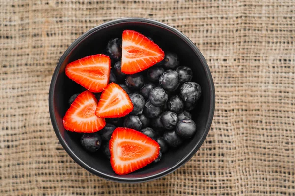 Top view of organic berries in bowl on sackcloth — Stock Photo