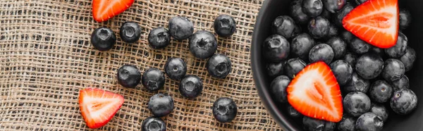 Top view of natural berries near bowl on sackcloth, banner — Stock Photo