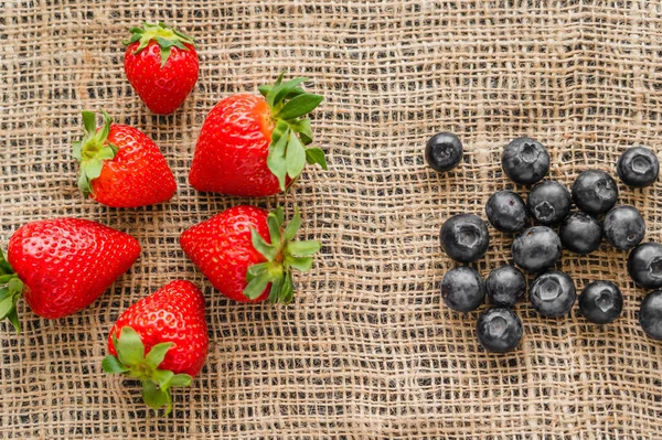 Top view of ripe strawberries and blueberries on sackcloth — Stock Photo