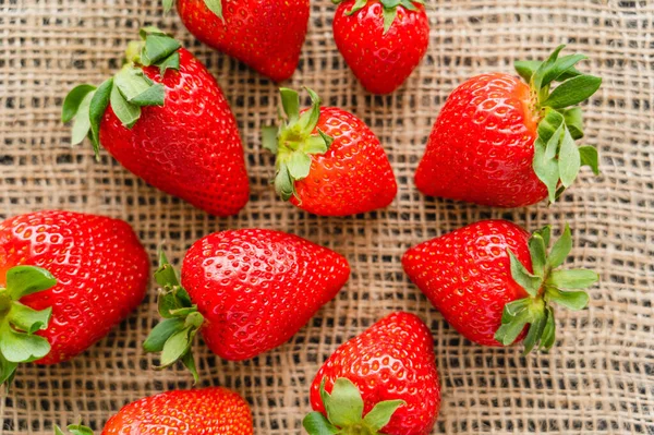 Top view of fresh strawberries with leaves on sackcloth — Stock Photo